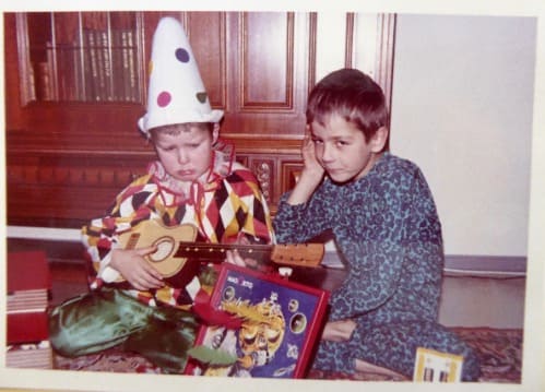 Auf dem Foto sind zwei Jungs zu sehen. Der Junge links auf dem Bild hält eine kleine Gitarre in seinen Händen.